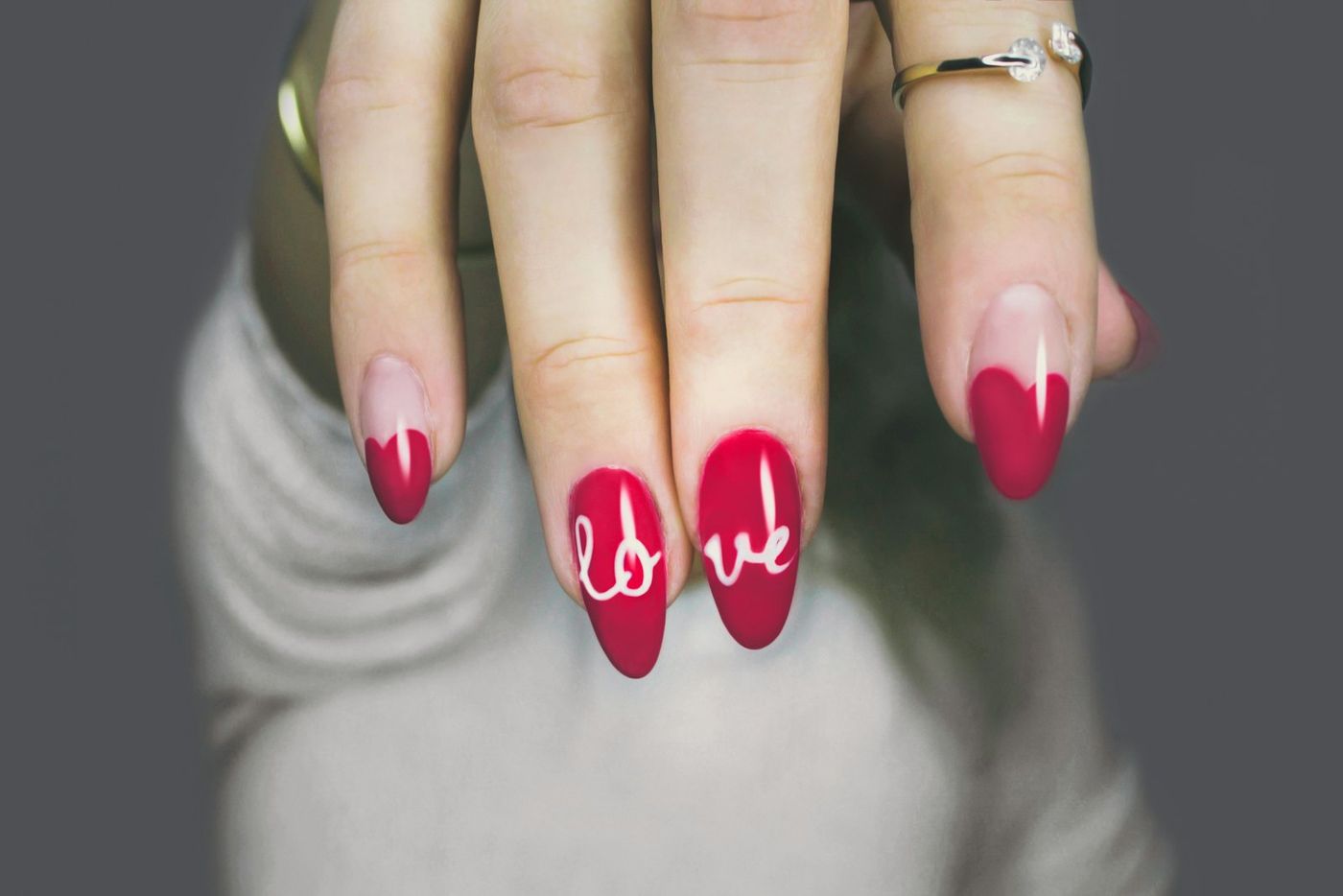 Cherry red nails with “love” hand-painted across two of them