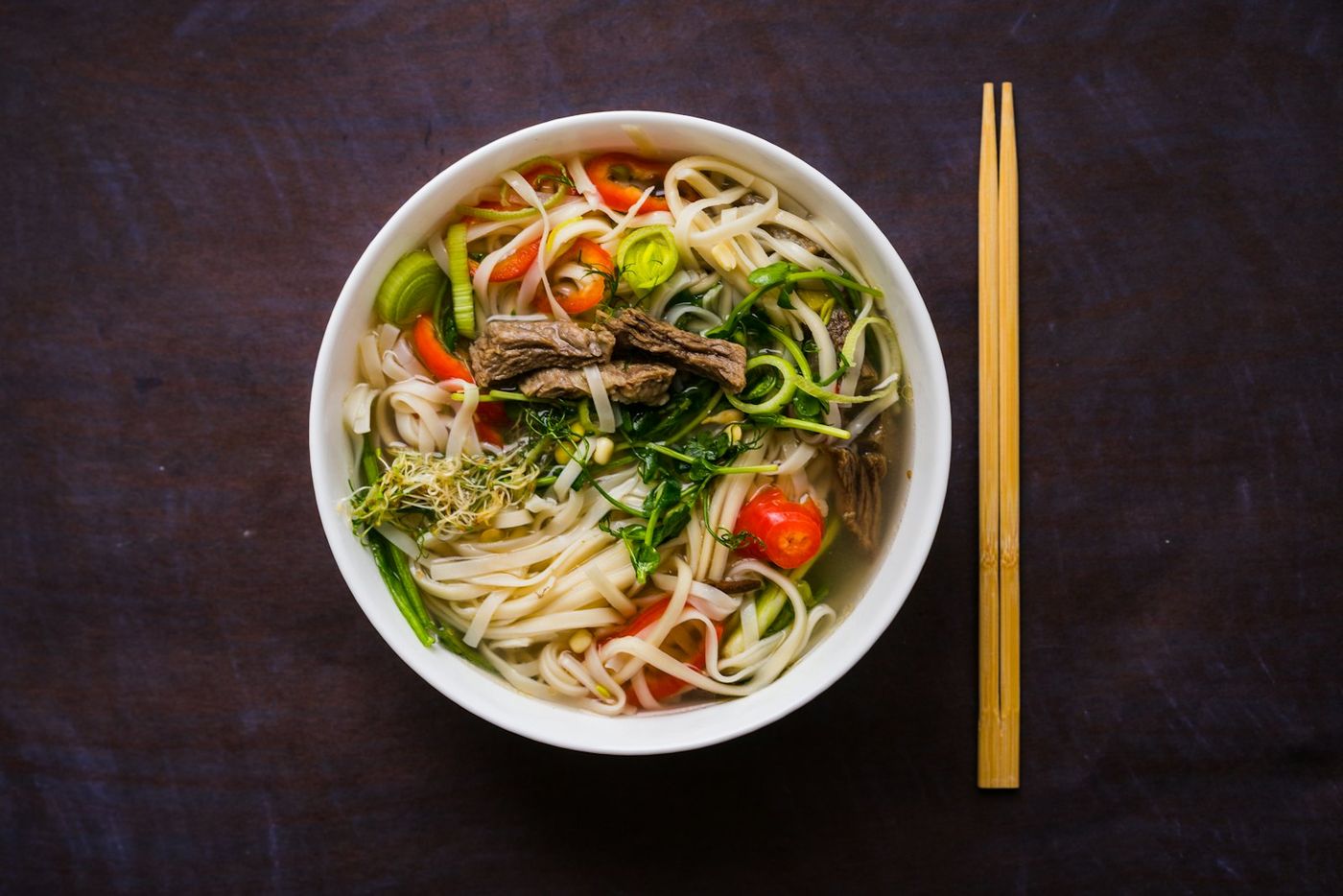 Phở with chilli and herbs, chopsticks on the side